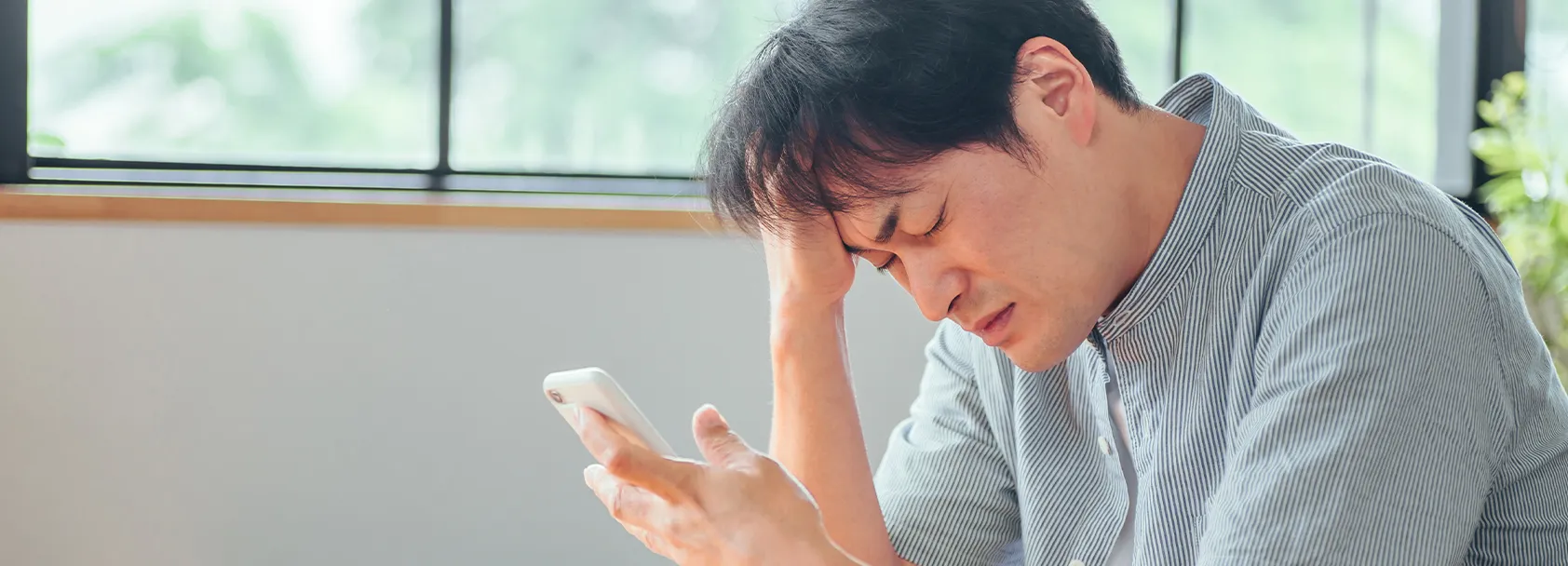 スマホを見て頭を抱えている男性